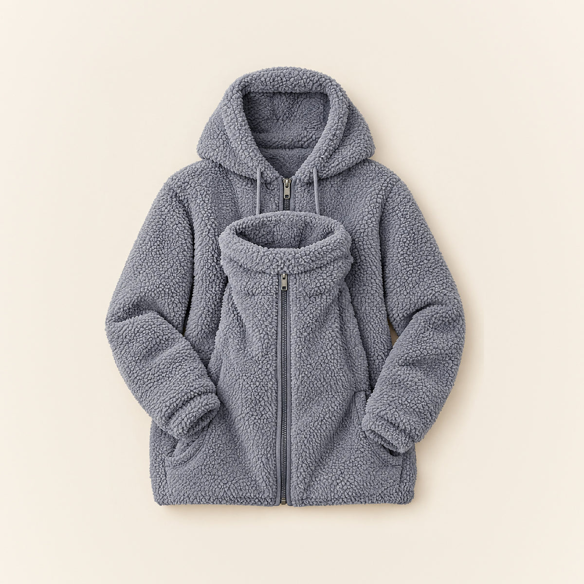 Graue 2-in-1 Kuscheljacke aus Teddyfleece mit Kapuze und eingesetztem Babyeinsatz, liegend auf cremefarbenem Hintergrund