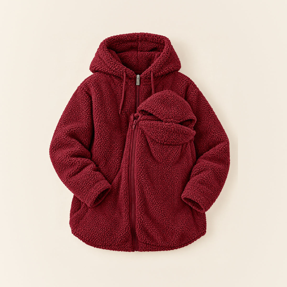 Dunkelrote 2-in-1 Kuscheljacke aus Teddyfleece mit Kapuze und Babyeinsatz, liegend auf cremefarbenem Hintergrund