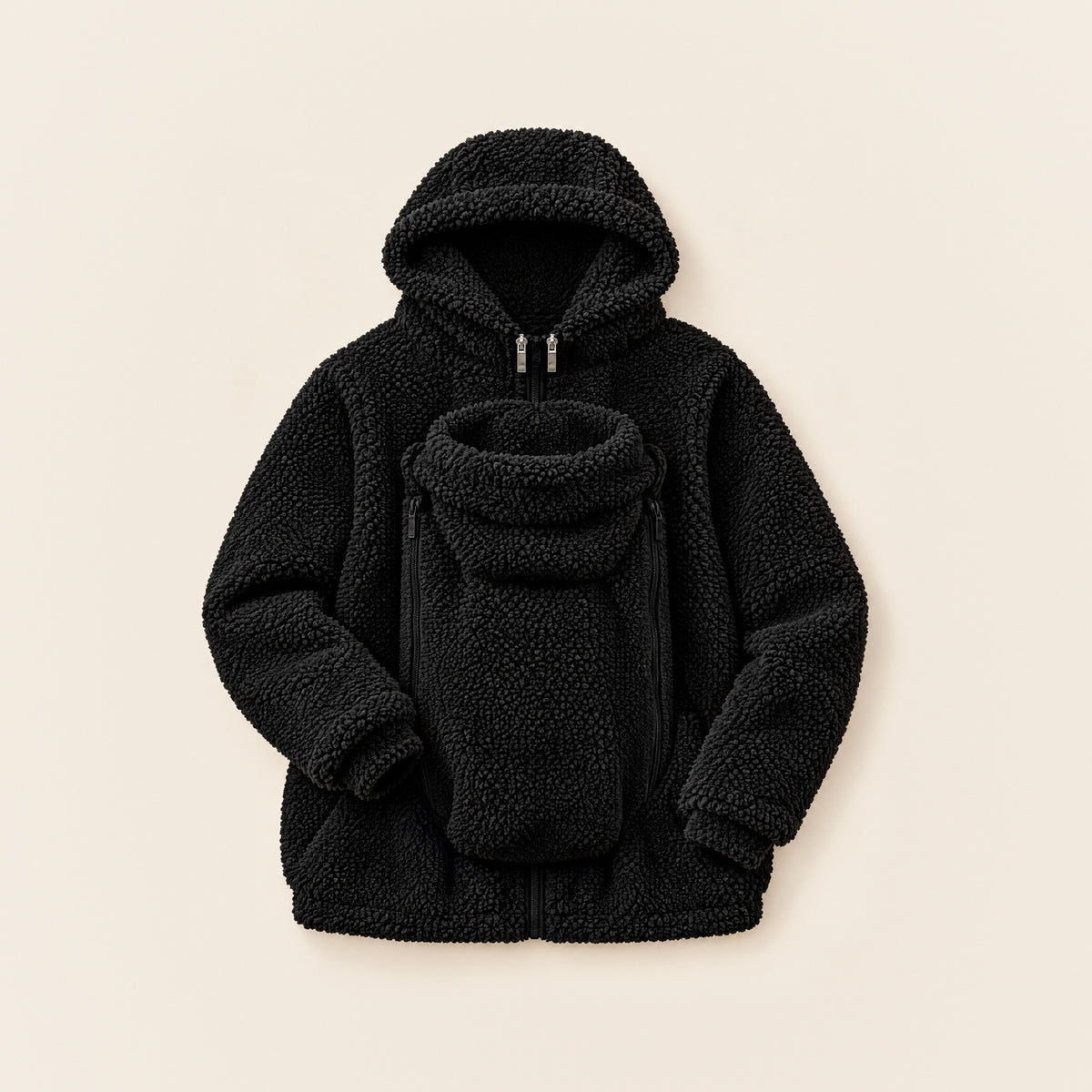 Schwarze 2-in-1 Kuscheljacke aus Teddyfleece mit Kapuze und eingesetztem Babyeinsatz, liegend auf cremefarbenem Hintergrund